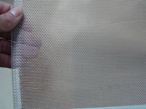 A roll of bright color aluminum mesh screen and one end is unfold in a man’s hand