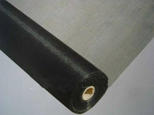 A roll of charcoal aluminum insect screen on the grey back ground, and one end is unfolded.
