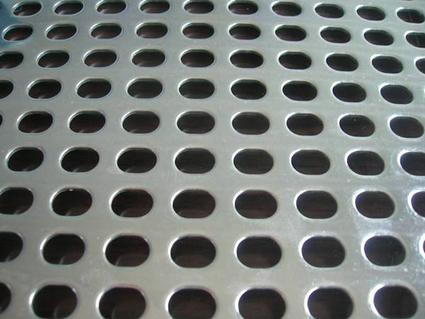 A piece of perforated aluminum metal sheet with oval shape holes in straight rows